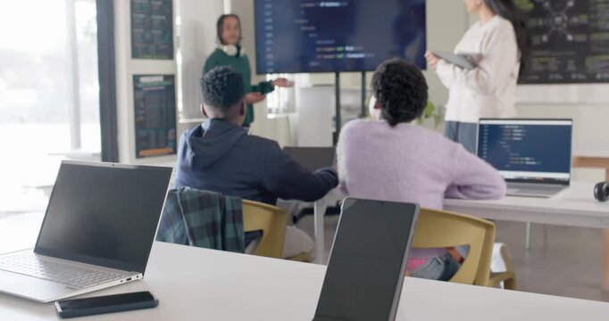 Diverse classmates presenting project after prompt in class, explaining code on large display