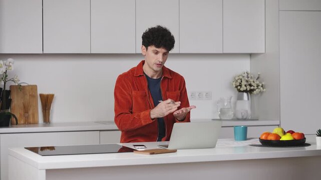 Young male game developer having online video call on laptop, talking to client