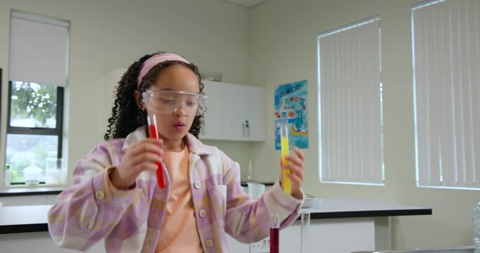 Picking test tubes, African American youth wearing goggles comparing colors, arranging rack in lab
