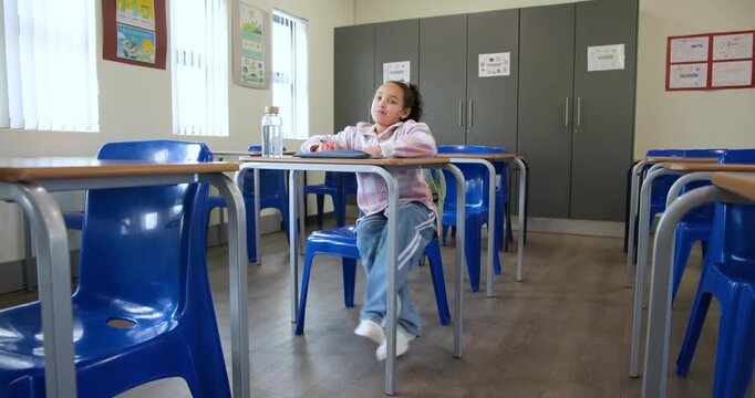 African American child working on assignment, writing in notebook at school desk, resting head
