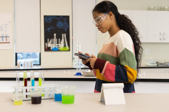 African American child in sweater and goggles testing tubes at school with calculator, copy space