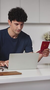 Smiling man holding German passport while applying for a visa on laptop at home
