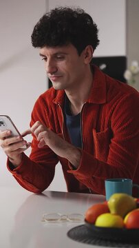 Happy young male texting on cellphone at home, receiving good news, technology