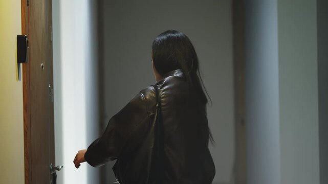 Young Asian woman opening her apartment door with a key, arriving back home