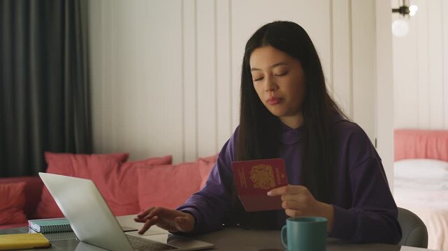 Happy Korean woman holding British passport while booking cruise tour online