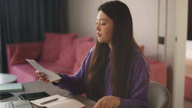 Young Korean woman opening envelope and reading a letter from university