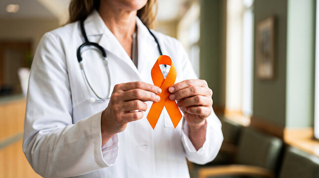 Doctor holding orange ribbon awareness symbol for leukemia and cancer support in clinic hallway.
