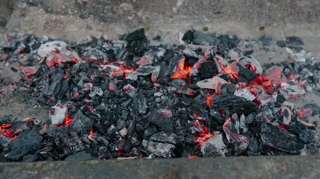 overhead shot of glowing embers on ash ground, vivid orange and red colors, dramatic burning scene, ashy.