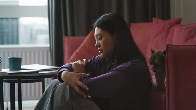 Unhappy Asian woman thinking about life problems while sitting on the floor