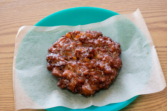 A delicious golden brown, fried apple fritter donut on a plate.