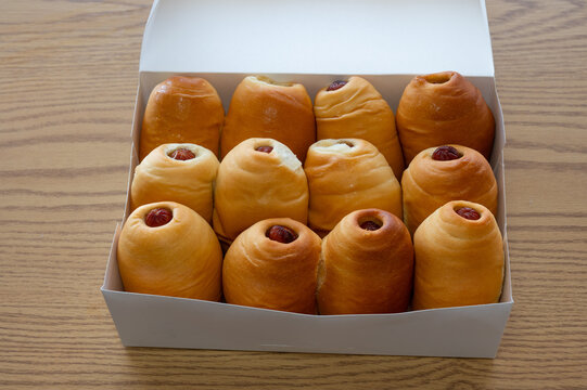A dozen delicious sausage rolls, or kolaches, organized in a box and ready to eat or deliver.