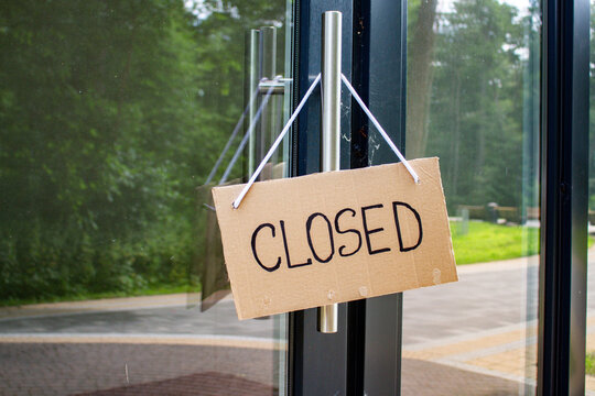 CLOSED sign hanging on small shop door. Small business shutting down due to financial crisis. Local business unable to survive economic pressure