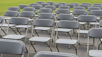 Fototapeta premium Rows of Empty Gray Folding Chairs Arranged Outdoors for a Formal Event or Public Gathering