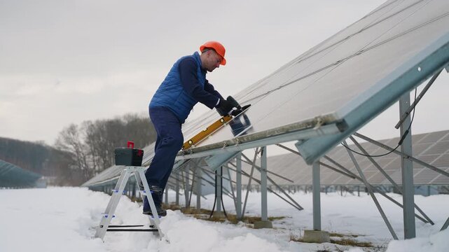 Technician installing solar panel using level tool in winter