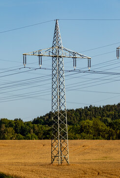 High voltage electricity pylon standing in golden wheat field in Germany