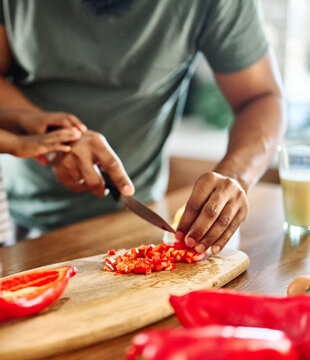 Young adult man cooking in kitchen. Close up of a Hand holding knife cut red pepperand  preparing and making healthy food.