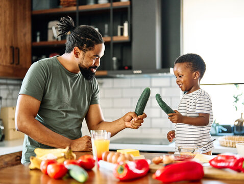 Portrait of a father and son preparing and eating breakfast and having fun in the kitchen at home