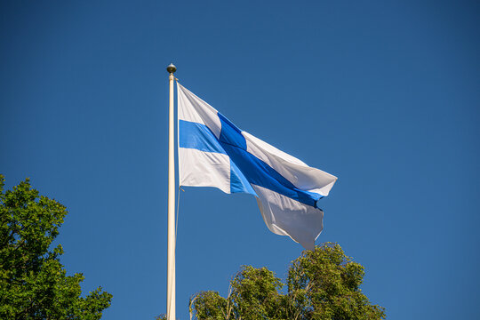 Finnish national flag waving against clear blue sky.