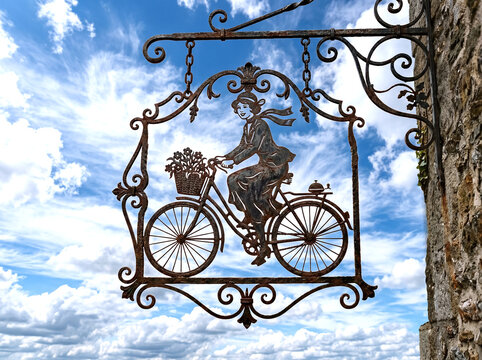wrought iron cut out hanging sign illustration of elegant woman riding bicycle