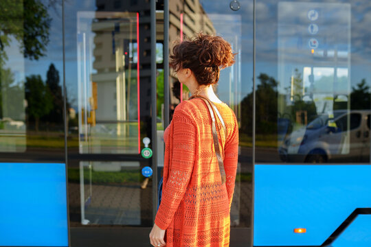 Independent young woman leaving modern tram after sustainable city journey