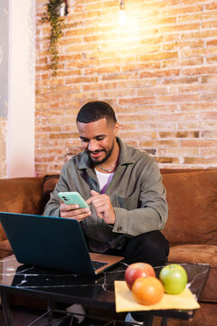Young man working from home using smartphone and laptop