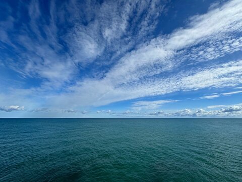 Clouds in blue sky over open sea.