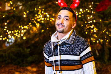 Man wearing reindeer antlers smiling during christmas celebration with festive lights © Ivi - Powerlightss