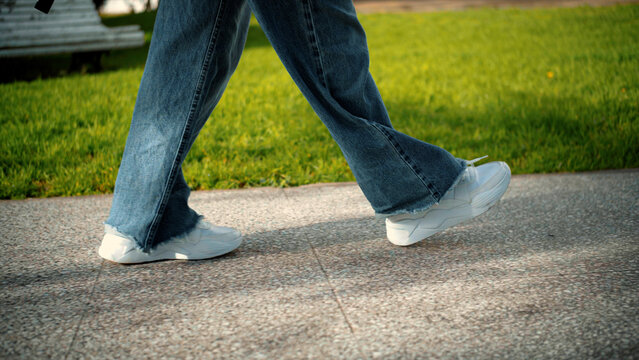 Close-up of an anonymous woman's feet walking on the street, representing movement, urban lifestyle, mobility, and everyday activity.