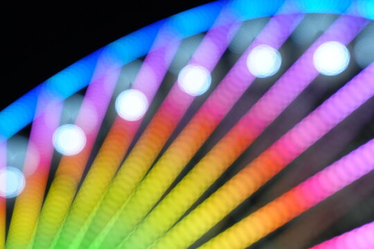 Soft focus bokeh of colorful lights on a ferris wheel at night
