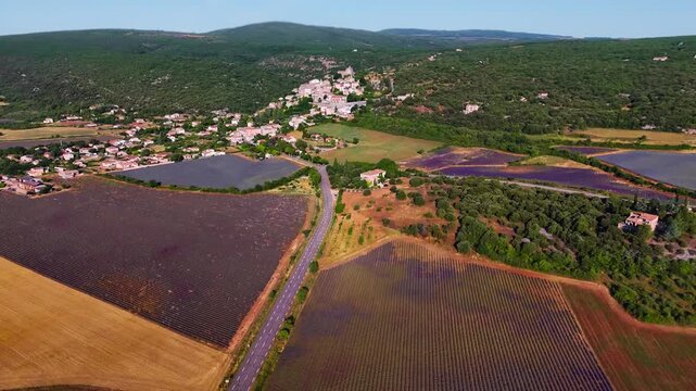 Aerial drone view Simiane-la-Rotonde among the mountains and blooming purple lavender fields. Provence-Alpes-Cote d'Azur region. High quality 4k footage