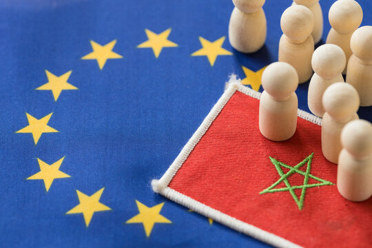 The symbol of Morocco and wooden human figures against the background of the European Union flag. Economic and social concept. Migration problem. EU external borders. Copy space
