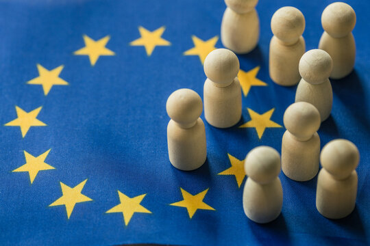 European Union migration crisis concept with wooden figures on EU flag background. Border control, illegal immigration, African refugees and geopolitical asylum policy.