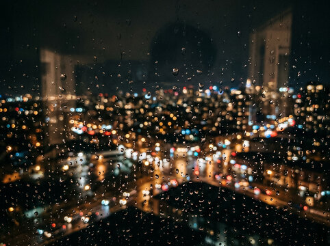 Gotas de lluvia en ventana con luces de ciudad desenfocadas de fondo