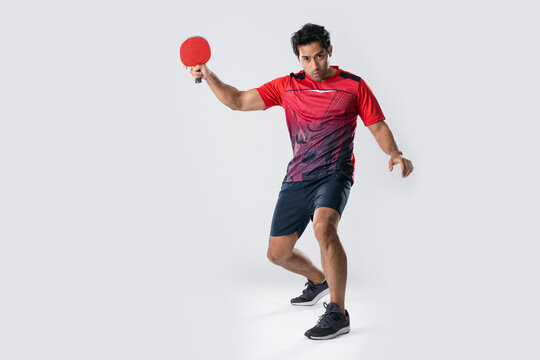 Man playing table tennis with a red paddle, focused on the game