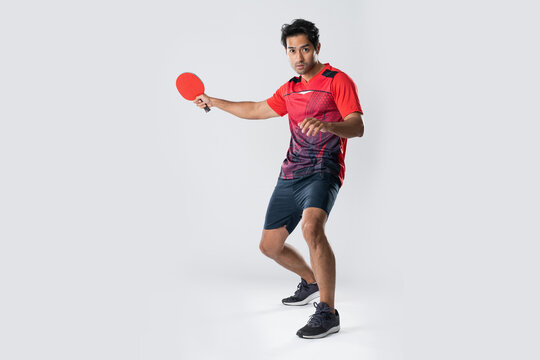 Man in athletic wear playing table tennis with a red paddle