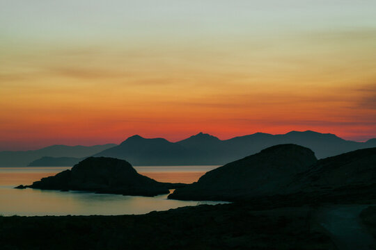 A beautiful sunrise over the dramatic shoreline of Mandrakia on the Greek island Milos. Calm water and vibrant colors. 