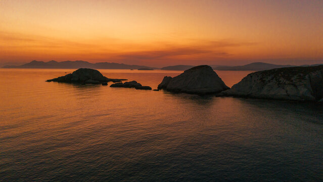 A beautiful sunrise over the dramatic shoreline of Mandrakia on the Greek island Milos. Calm water and vibrant colors. 