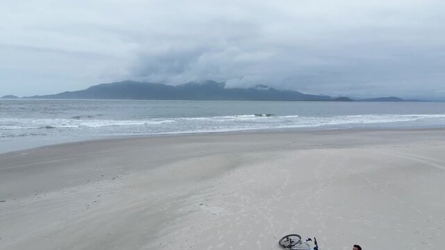 Couple having a picnic with a dog and bicycles by the sea. Ilha Comprida, Sao Paulo