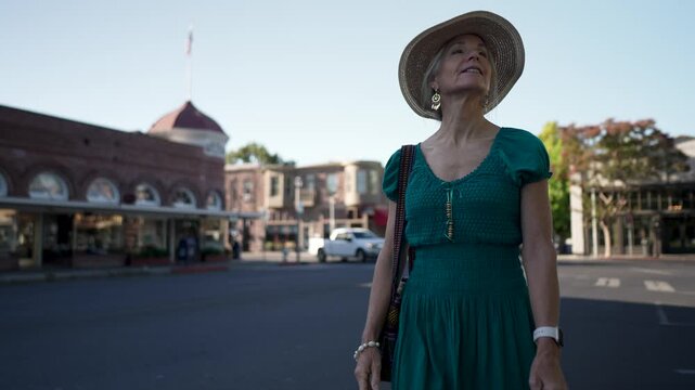 Happy senior woman walks near historic Sebastiani Theater in Sonoma California on a sunny morning, taking in the sights around her