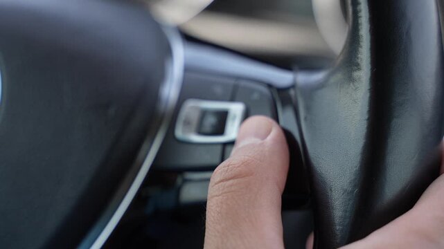 Close Up of Hand Pressing Steering Wheel Button While Driving