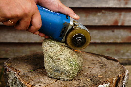 Man working with angle grinder in the backyard of a countryside house