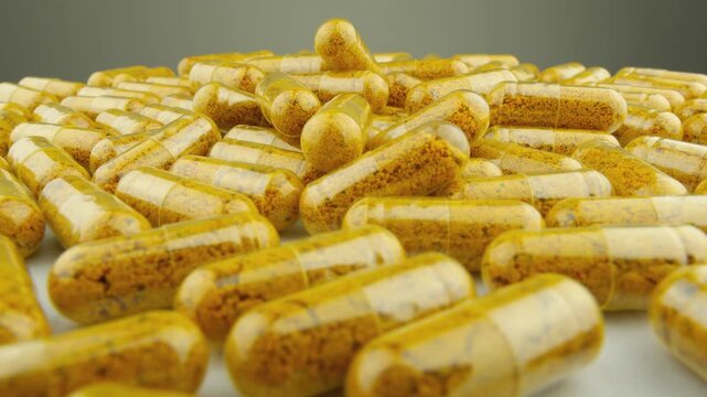 Numerous yellow supplement capsules are displayed in a random arrangement, emphasizing their glossy appearance. The image conveys themes of health, wellness, and modern nutrition trends