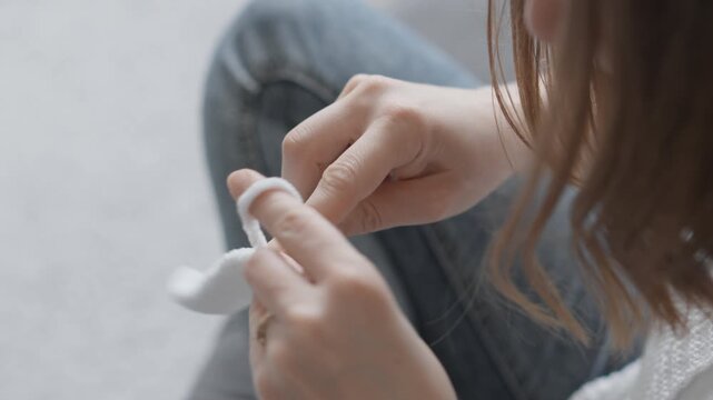 A woman skillfully knits with white yarn, demonstrating patience and creativity in a tranquil setting. The image highlights the calming process and tactile experience of handcrafting