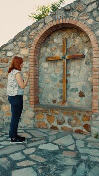 Woman prays for world peace at outdoor Christian religious crucifix