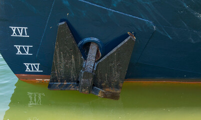 Dark blue vessel hull with depth draft marks and stockless anchor anchored in water © catocala