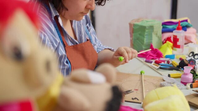 Focused female artist creating a hand puppet in a workshop
