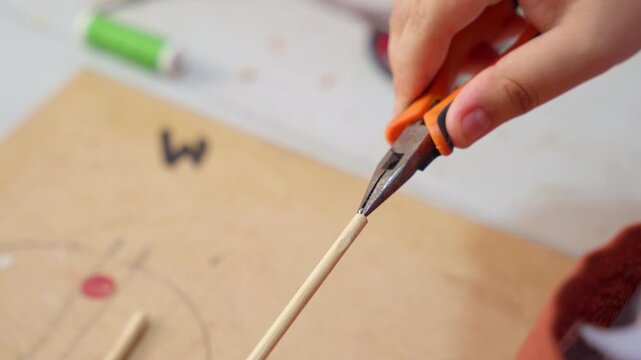 Person crafting puppet with pliers in workshop