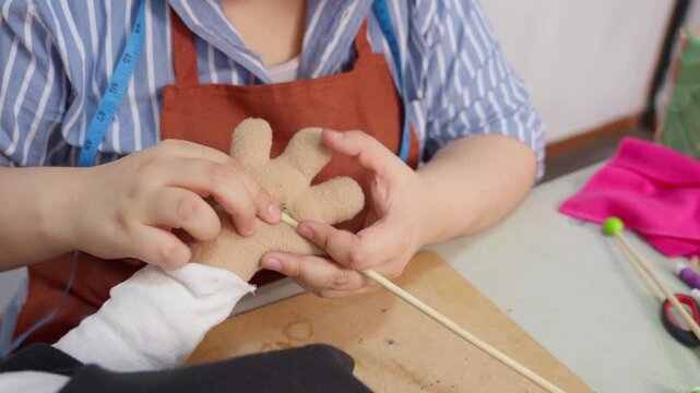 Artisan puppet maker sewing fabric hand in workshop