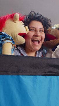 Joyful puppeteer playing with hand puppets