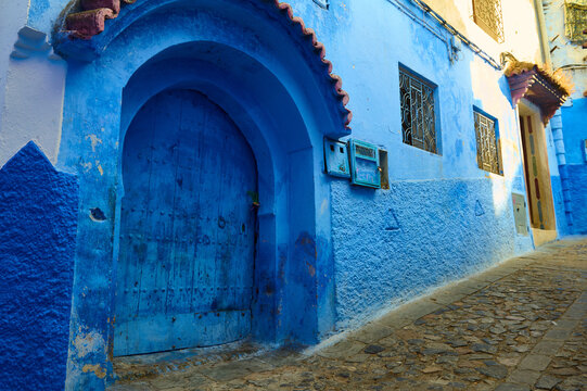 Blue door and arched doorway on a narrow street in Chefchaouen, Morocco